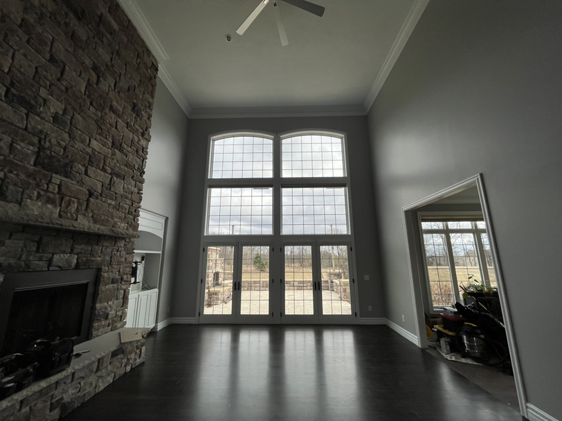 Empty two-story great room with stone fireplace after interior paint